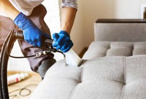 man-wearing-blue-gloves-cleaning-couch